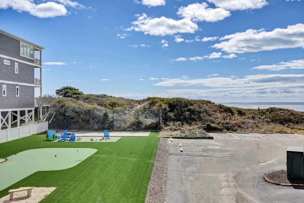 A lush green lawn with blue chairs facing the ocean, offering stunning water views. The area is ideal for relaxing or socializing, with a sense of space and openness characteristic of a beachside escape.