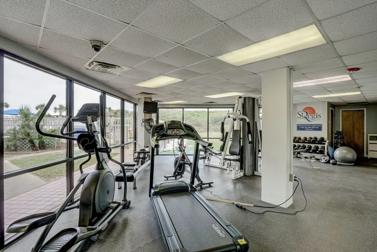 An energetic fitness center with treadmills, elliptical machines, and weight training equipment, all set up in a well-lit, modern interior. The space looks clean, motivating, and suitable for a variety of workouts.