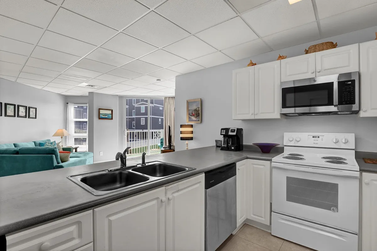 A stylish kitchen island with seating is the centerpiece, surrounded by modern appliances, a sink, and an open view into the living area. The design encourages seamless interaction between cooking, dining, and entertaining.
